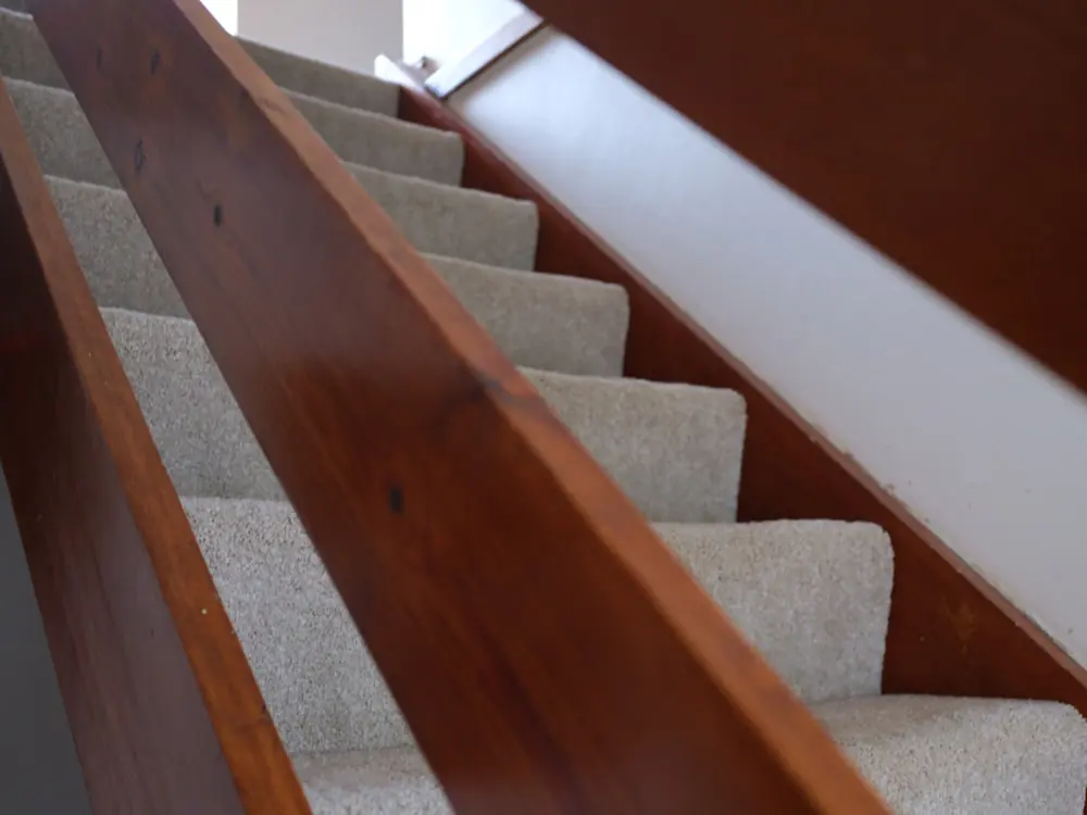 Met tapijt gestoffeerde trap met houten leuning