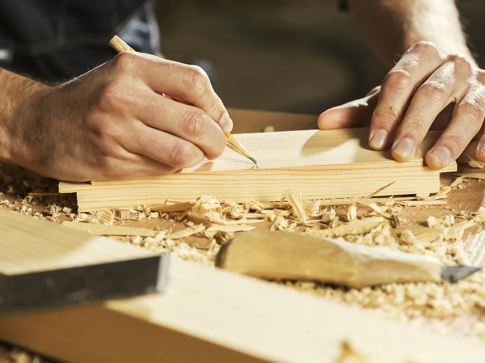 Vakman tekent een houten plank af met een potlood