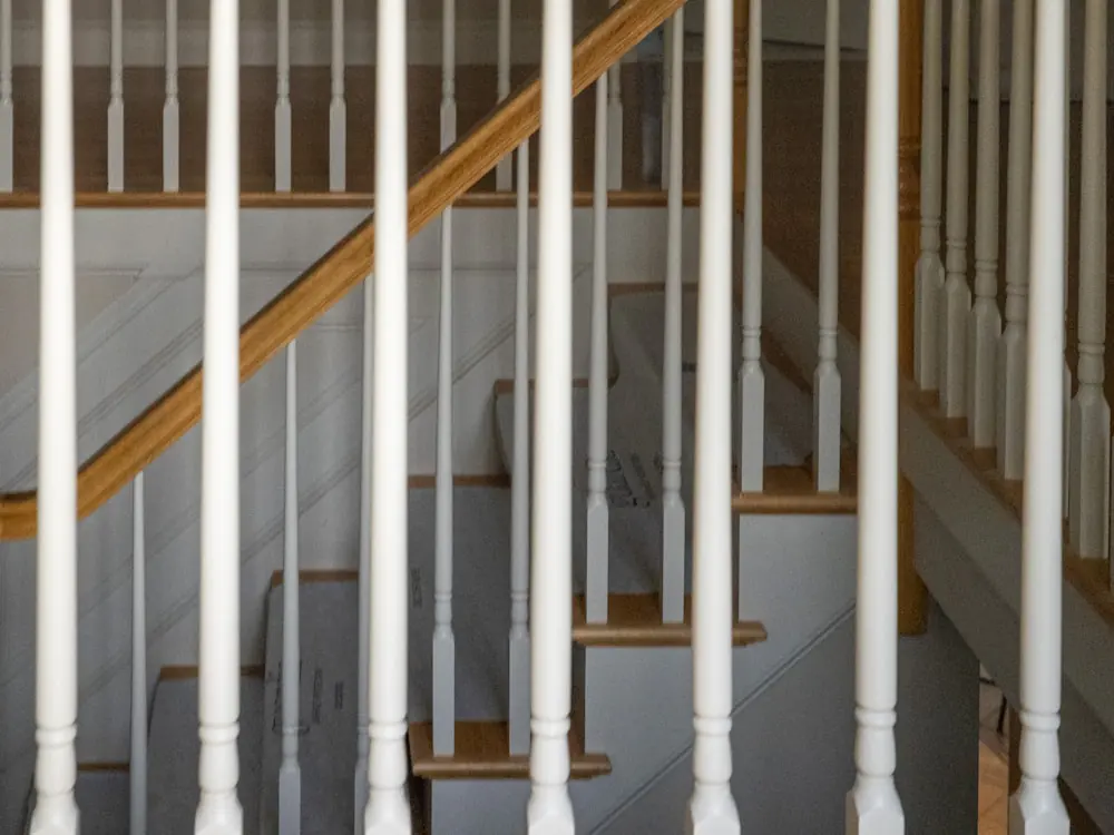 Houten trap met witte, geschilderde balusters en leuning